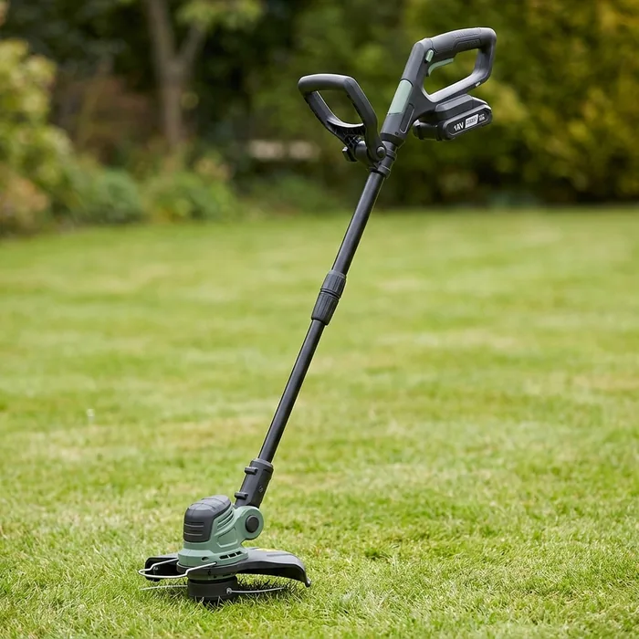 Cordless grass trimmer standing on a mown lawn